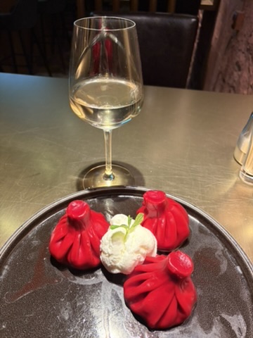 Rote Dessert-Khinkali mit Eis und einem Glas Weißwein