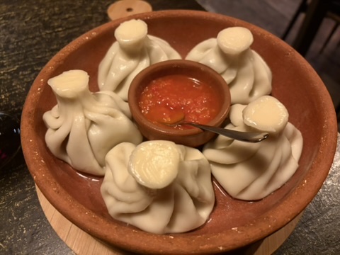 Khinkali im Tonschälchen mit roter Adjika-Sauce in der Mitte