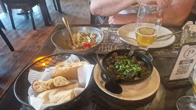 Georgischer Tisch mit Shotis Puri, Tomatensalat und Fleischgericht im Ketsi
